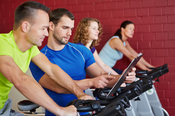Fitnesstrainer redet mit Mann beim Spinning