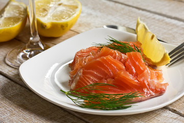 Salmon on plate with lemon on wooden background