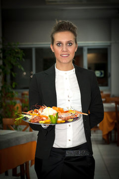 Young waitress serving food at a restaurant.