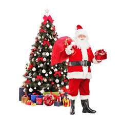 Santa Claus with bag standing next to a Christmas tree