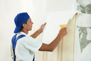 painter worker peeling off wallpaper