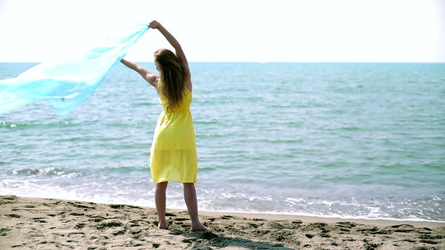 Young woman with waving sarong at the beach 