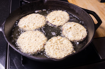 Five slices of eggplant in frying pan