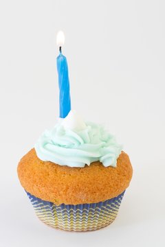 Foto Stock cupcakes azzurro con candelina accesa | Adobe Stock