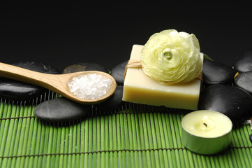 herbal salt in spoon with stones and ranunculus flower on soap