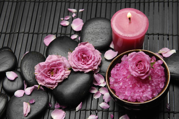 Pink herbal salt in bowl with two rose and stones with candle