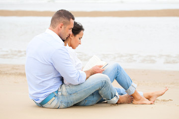 Fototapeta na wymiar Couple reading book on the beach