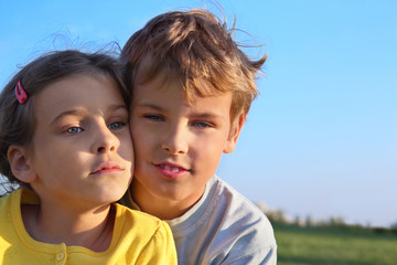 Boy and girl together smile at background of blue sky