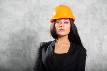 Beautiful brunette girl in coat, helmet pose in photo studio