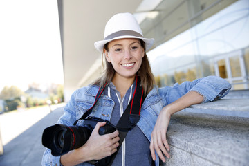 Smiling reporter standing outside with photo camera