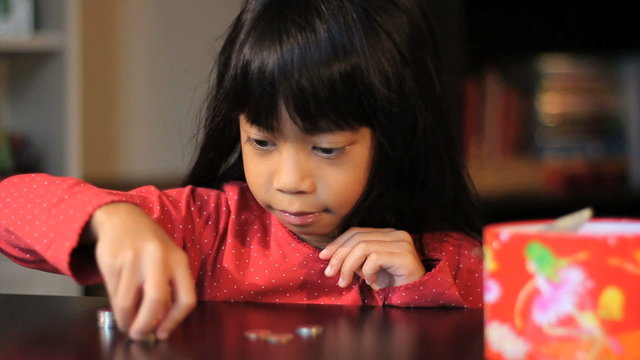 Excited Six Year Old Asian Girl Counts Her Money