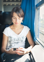 Young woman texting with her phone while traveling by train
