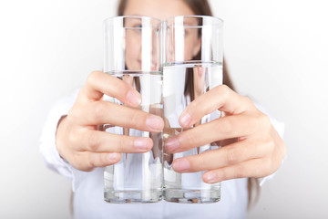 Junge Frau hält 2 Gläser Wasser zusammen