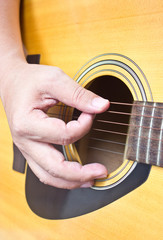 Close up of hand playing acoustic guitar.