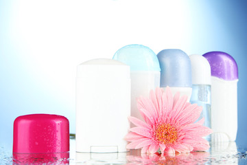 deodorant botttles with flower on blue background