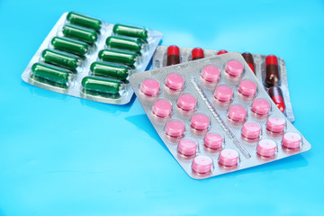 Capsules and pills packed in blisters, on blue background