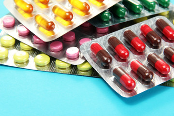 Capsules and pills packed in blisters, on blue background