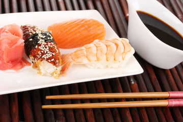 delicious sushi served on plate on bamboo mat