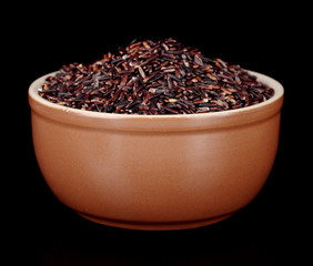 Black rice in brown bowl isolated on black
