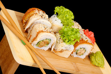 Tasty rolls served on wooden plate isolated on black