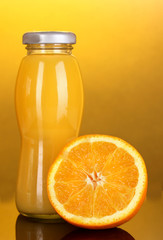 Fototapeta na wymiar Pyszny sok pomarańczowy w butelkę i pomarańczowy obok