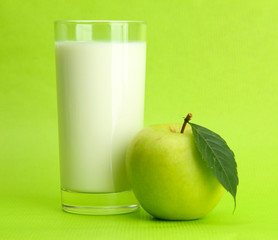Glass of kefir and apple, on green background
