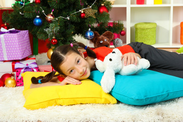 Little girl sleeping near christmas tree
