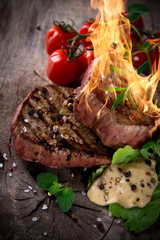 Grilled bbq steaks with fire flames