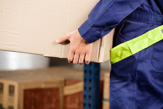 Foreman Carrying Cardboard Box At Warehouse