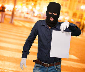 Man wearing a robber mask showing a blank paper