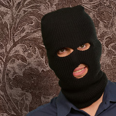Man wearing a robber mask showing a blank paper