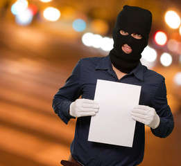 Man wearing a robber mask showing a blank paper