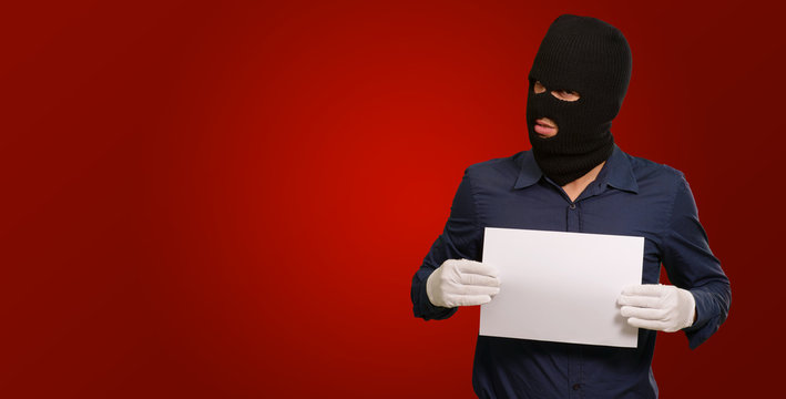 Man wearing a robber mask showing a blank paper`