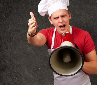 portrait of young cook man screaming with megaphone and gesturin