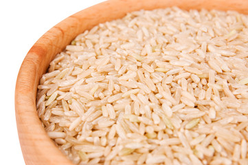 Raw brown rice in wooden bowl close-up over white background