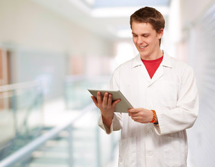 portrait of young academic holding a digital tablet at entrance