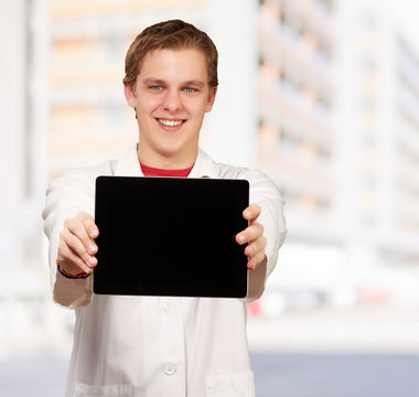 portrait of young man showing digital tablet against a building