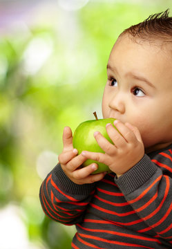Portrait Of Baby Boy Eating Green Apple