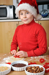 Junge mit Weihnachtsmütze backt Plätzchen