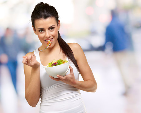 Young woman holding and eating salad