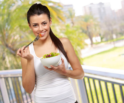 Young woman holding and eating salad