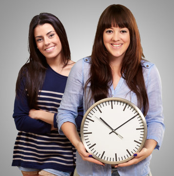 Portrait Of Happy Women Holding Clock