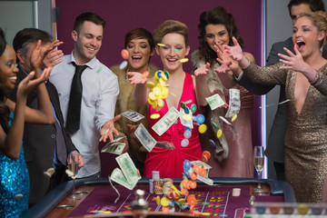People throwing chips and cash on roulette table