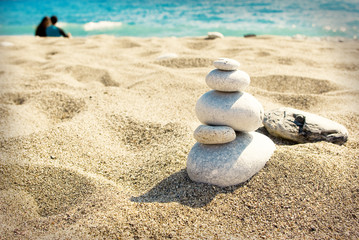 White stones on sandy beach with a couple on back