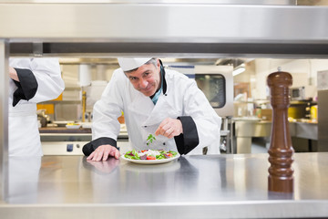 Smiling chef garnishing salad