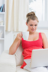 Woman drinking a coffee while using laptop