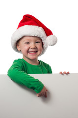 Junge mit Weihnachtsmannmütze zeigt auf Schild