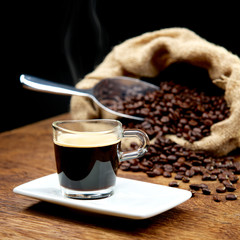 Heißer Espresso auf Tisch mit Kaffeebohnen im Sack und Schaufel