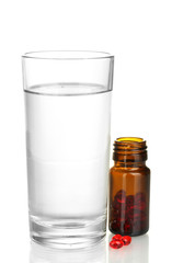 A glass of water and pills isolated on white close-up