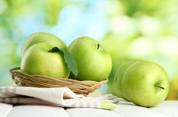 Ripe green apples with leaves in basket,